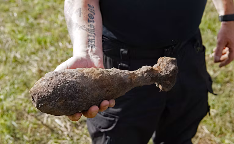 Per Olsen fandt lørdag en mortergranat med sin metaldetektor på marken mellem Tiphedevej og Kvie Søvej. En af bomberydderne viser granaten frem